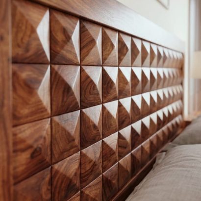 Solid Sheesham wood designer bed featuring a geometric carved headboard and footboard in a modern luxury bedroom